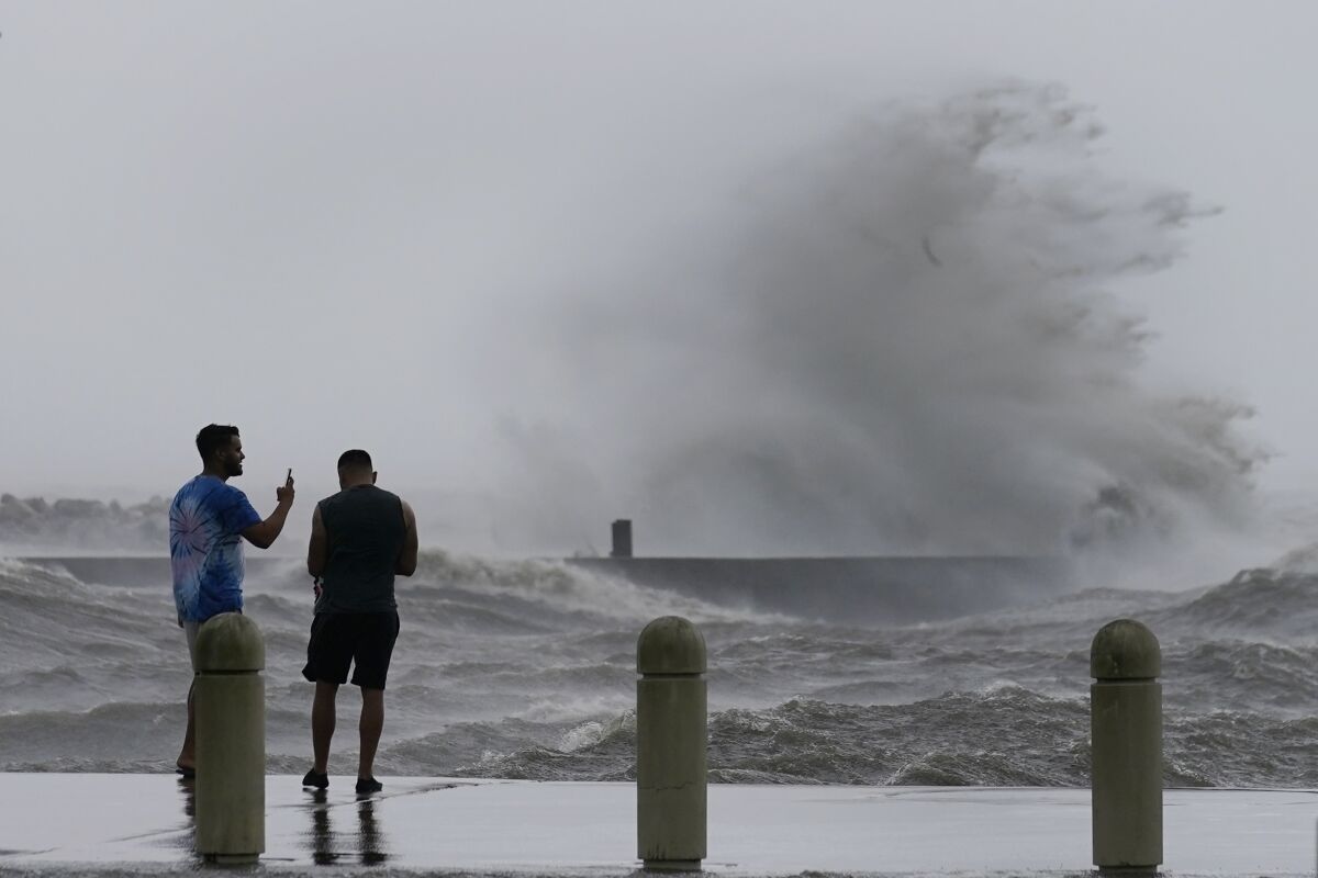 Two people check out the high waves from a walkway.