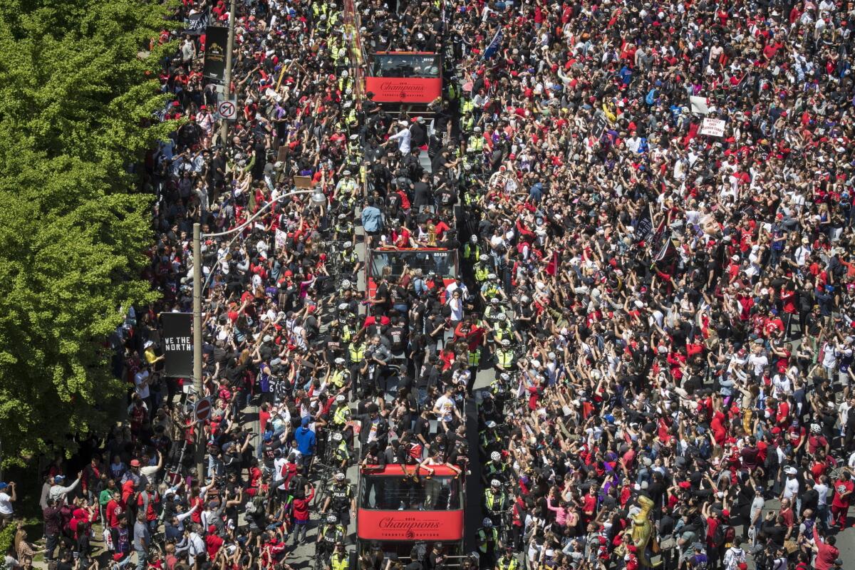 Members of the Toronto Raptors ride on buses during a victory parade Monday in Toronto.