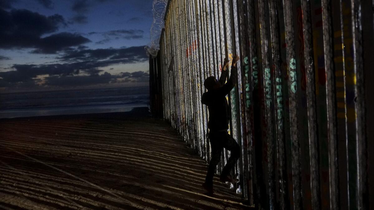 A man prepares to climb the U.S.-Mexico border wall Sunday in Tijuana.
