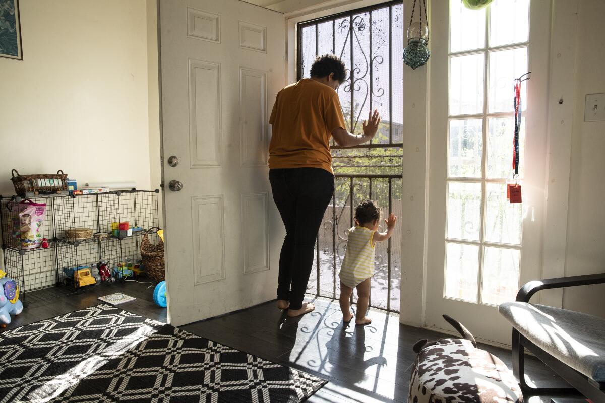 Jay Brissette, a la izquierda, y Azul, de 1 año, miran por la puerta de su casa de Los Ángeles en agosto.