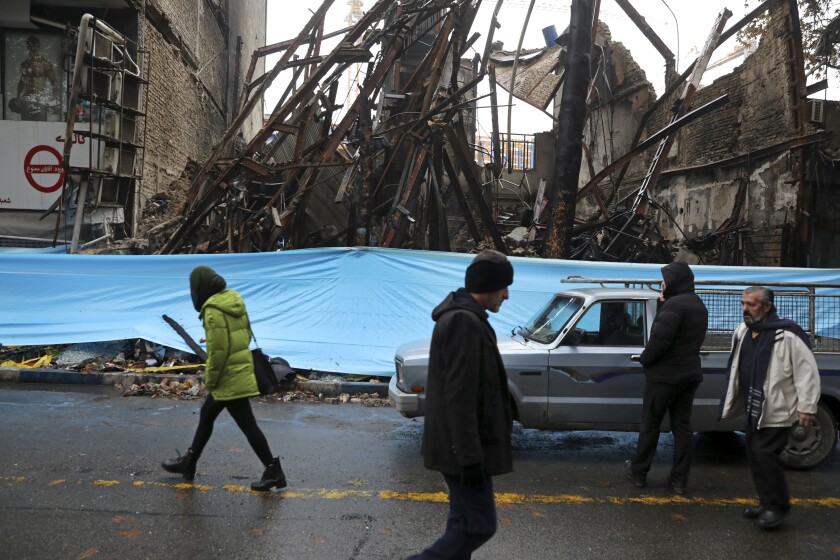 People walk past buildings that were burned during recent protests in Shahriar, Iran, about 25 miles southwest of the capital, Tehran, on Nov. 20, 2019. Amnesty International says at least 208 people in Iran have been killed amid protests over sharply rising gasoline prices and a subsequent crackdown by security forces. The country has yet to release any nationwide statistics about the unrest last month.