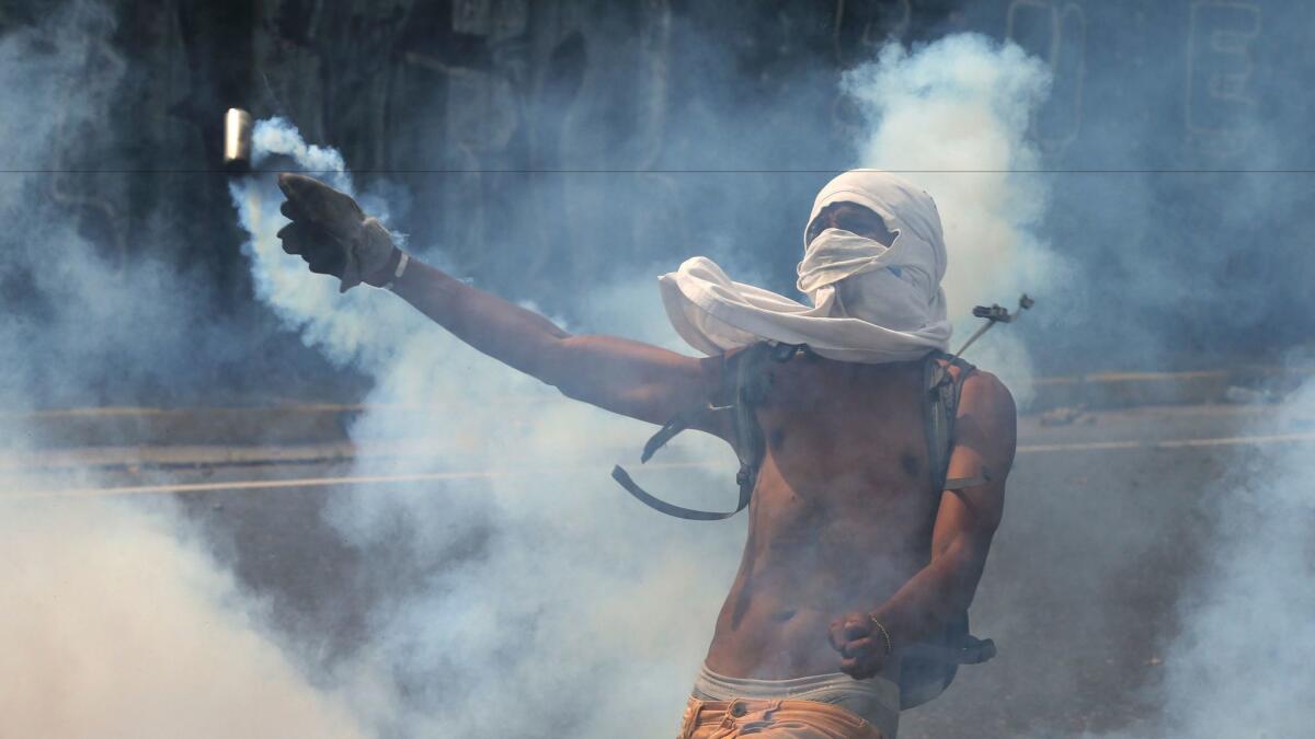 A demonstrator tosses a canister of tear gas back toward security forces during an antigovernment protest in Caracas, Venezuela. More large protests are expected around the country Wednesday.