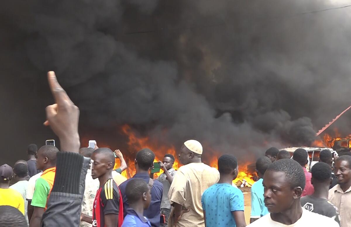 A crowd of people with fire and smoke in the background