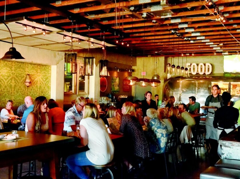 Patrons gather around a communal table in the dining room at OB Warehouse in Ocean Beach.