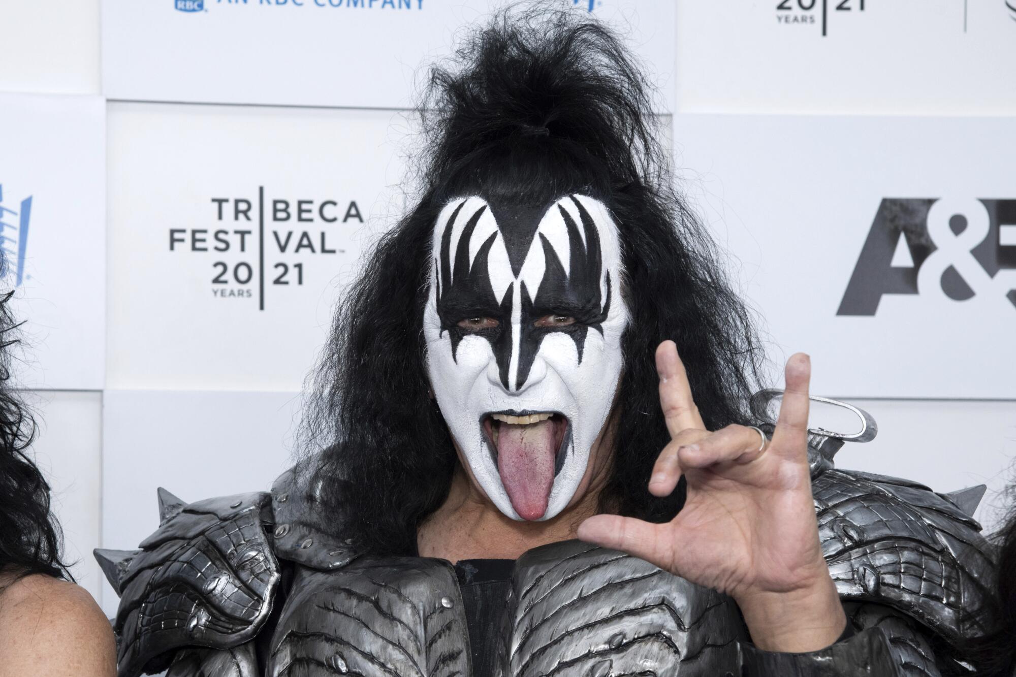 Gene Simmons wears full Kiss makeup while sticking out his tongue and making a rock-and-roll sign with his left hand