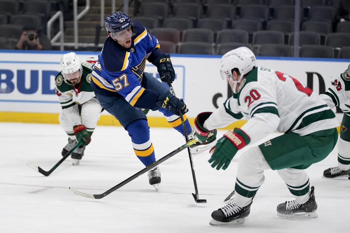 St. Louis Blues' David Perron (57) shoots as Minnesota Wild's Marcus Johansson (90) and Ryan Suter (20) defend during the second period of an NHL hockey game Friday, April 9, 2021, in St. Louis. (AP Photo/Jeff Roberson)