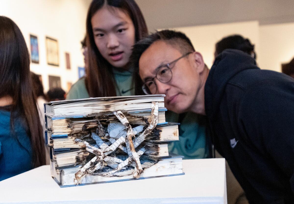 Sara Kong and her father, Tim Kong, examine a sculpture on display at the "Color It Orange" exhibit.