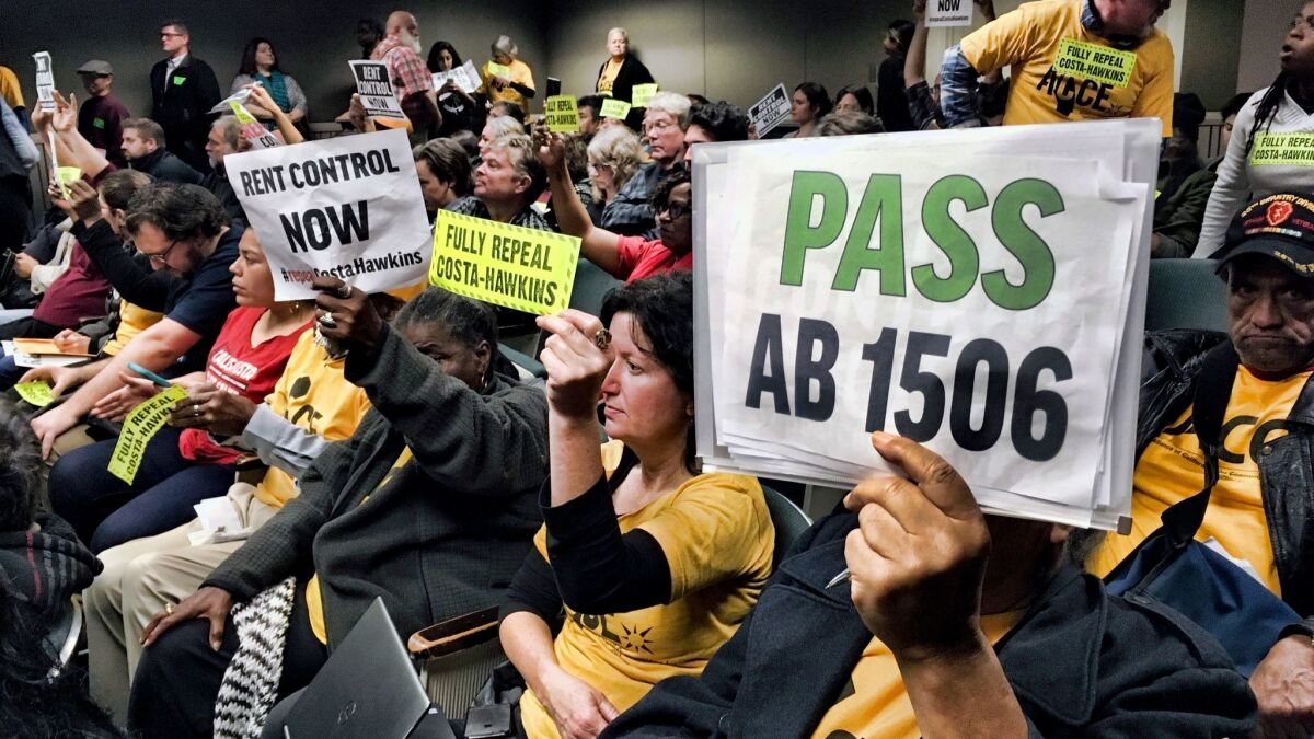 Voters hold signs demonstrating their support for legislation that would allow California communities to expand rent control policies during a legislative hearing in Sacramento on Thursday.