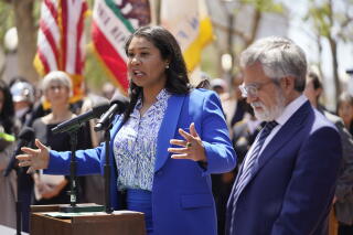 Supervisor Aaron Peskin listens as San Francisco Mayor London Breed speaks at an outdoor hearing.