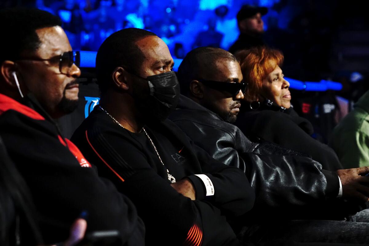 Three men and a woman in seats, watching a sporting event