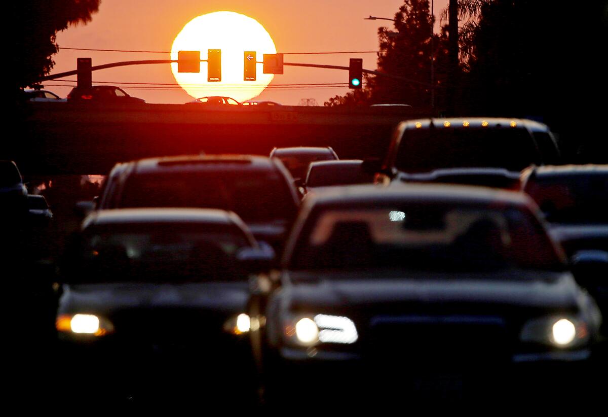 Traffic stacks up at Wardlow Road and the 405 Freeway in Long Beach as the sun sets behind a reddish veil of smog.