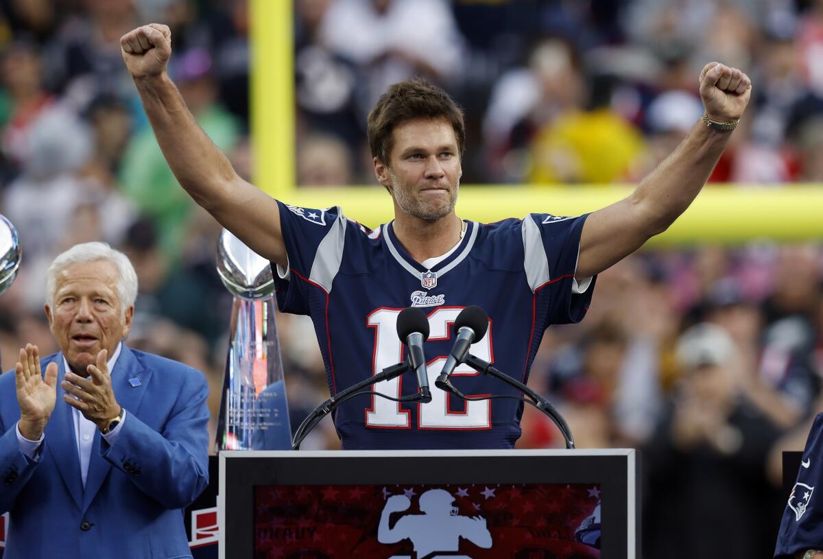 Former New England Patriots quarterback Tom Brady reacts on the stage in front of owner Robert Kraft and Brady's daughter