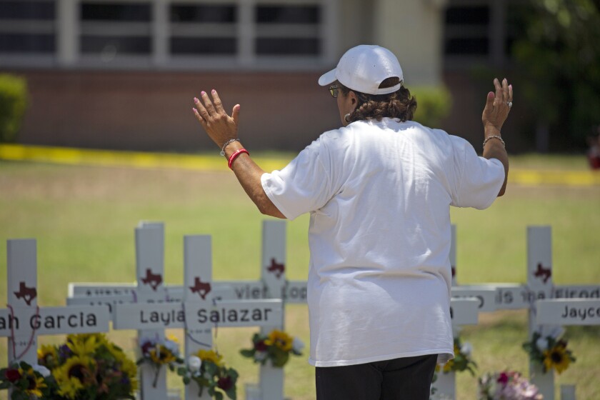 Una mujer reza el jueves 26 de mayo de 2022 frente a cruces de madera con los nombres de las víctimas de un tiroteo