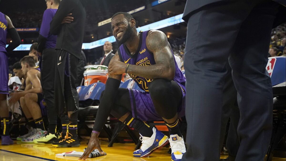 LeBron James grimaces in pain on the bench after suffering an injury in the Christmas Day game against the Warriors.