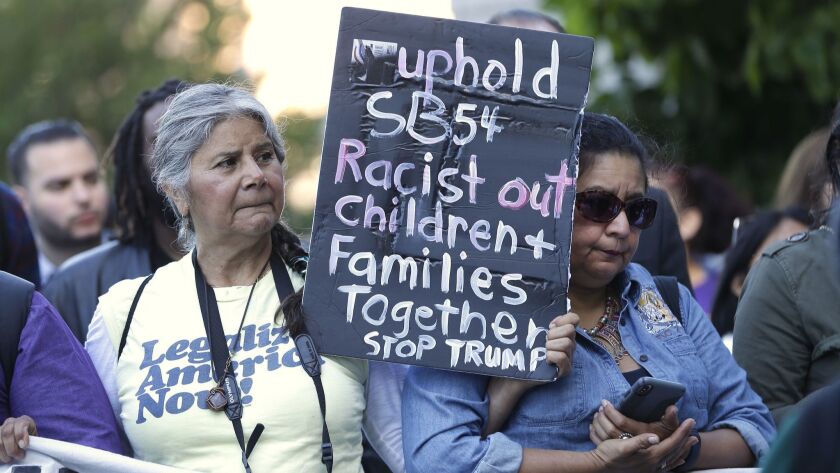More than 100 protesters demonstrated Wednesday outside the federal courthouse in Sacramento, where a federal judge heard arguments over the U.S. Justice Department's request to block three California laws that extend protections to people in the country illegally.