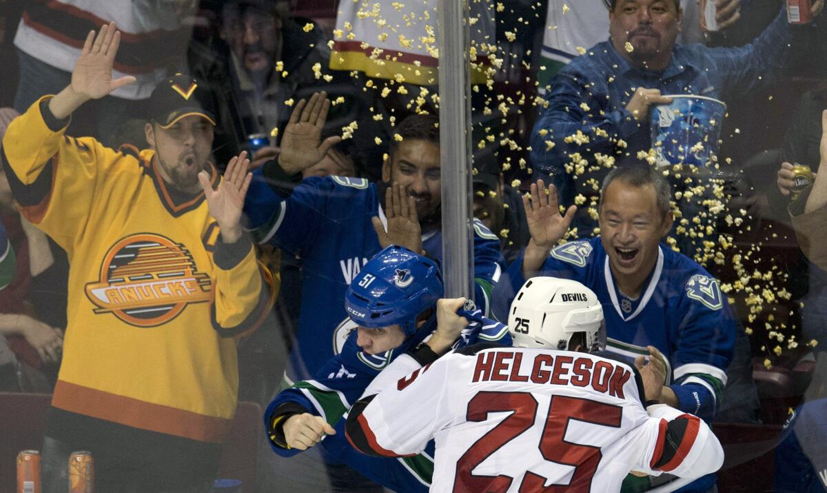 Fans cheer as Vancouver Canucks right wing Derek Dorsett fights with New Jersey Devils defenseman Seth Helgeson 