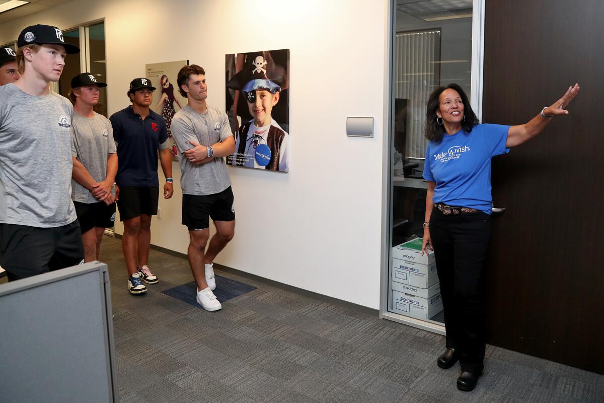 Gloria Crockett, chief executive and president of Make-A-Wish Orange County & the Inland Empire, shows athletes around.