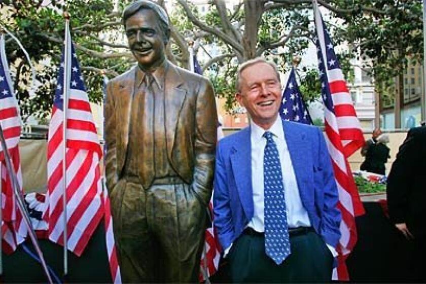 Former mayor Pete Wilson stands by his bronze statue in downtown San Diego.