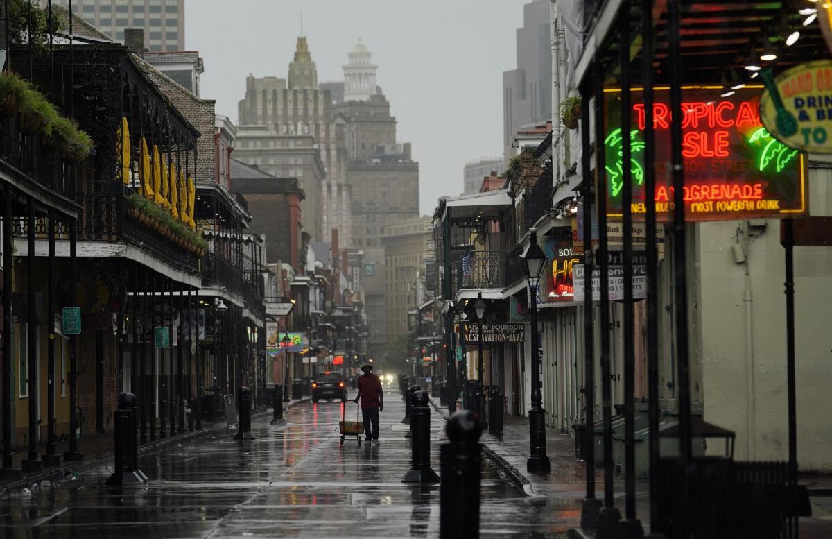 A man pulls a cart down a mostly deserted Bourbon Street in the French Quarter of New Orleans