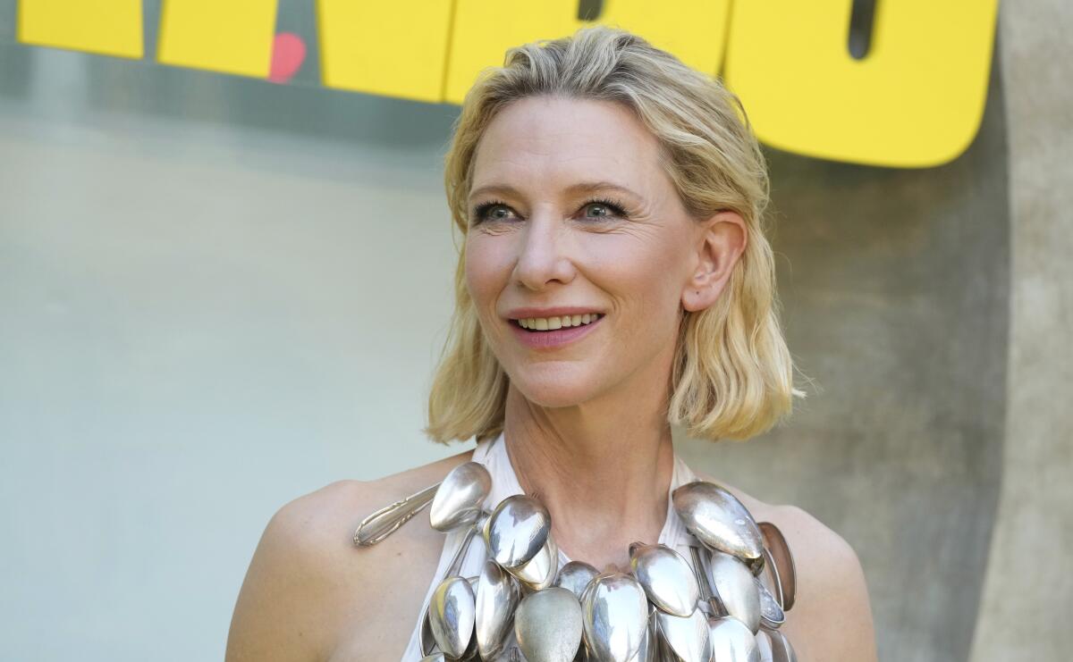 A smiling Cate Blanchett wears a halter top covered with spoons.