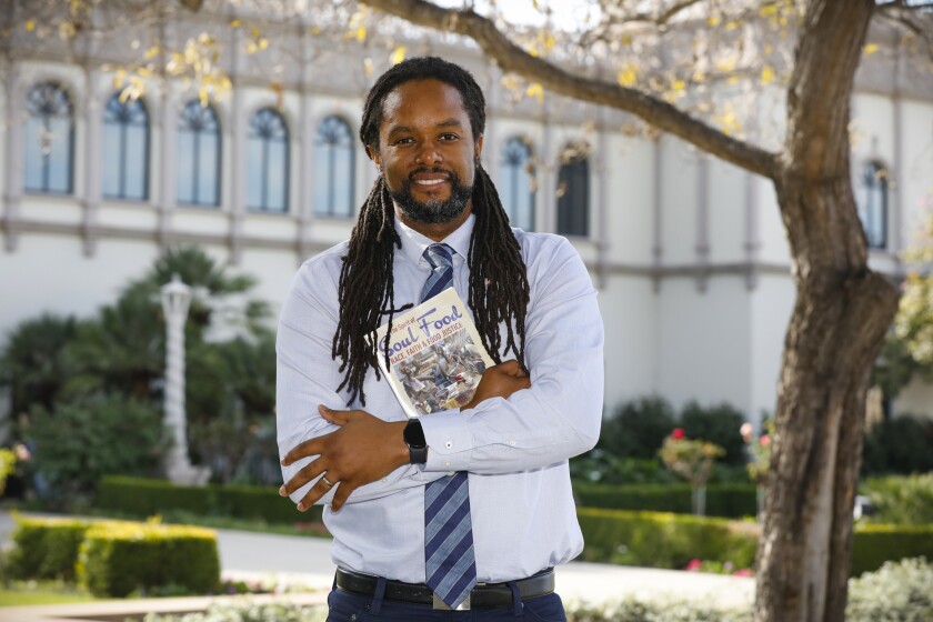 Christopher Carter, pictured outdoors and holding a copy of his book, "The Spirit of Soul Food" 