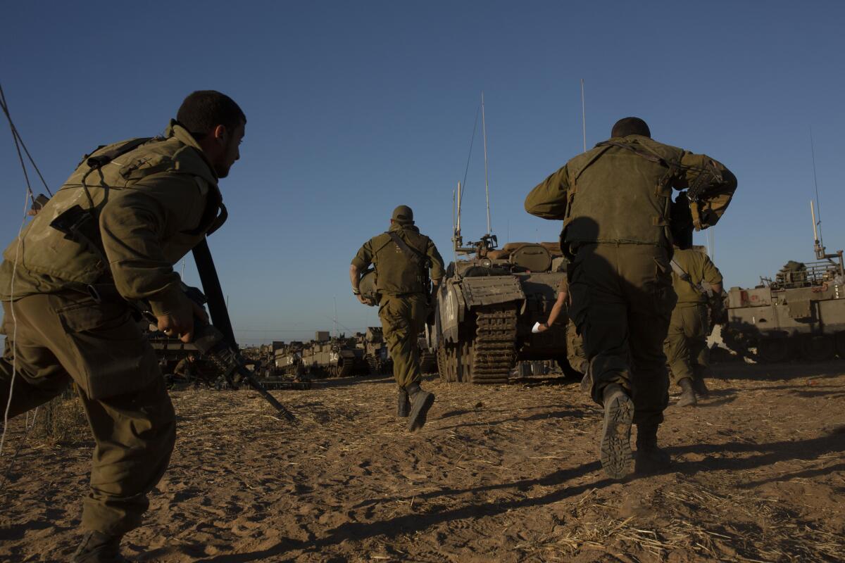 Soldiers running toward armored vehicles.