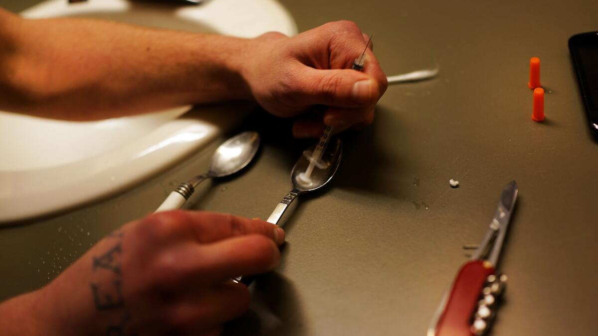 A user prepares to shoot up heroin.
