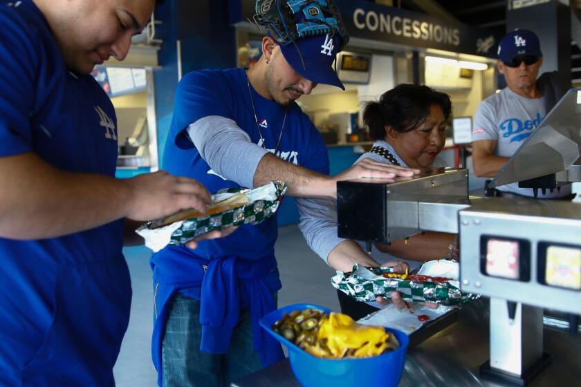 LOS ANGELES, CALIF. - MAY 27: Eric and Steve Soto put condiments on their Dodger Dogs at Dodger Stadium on Monday, May 27, 2019 in Los Angeles, Calif. (Kent Nishimura / Los Angeles Times)