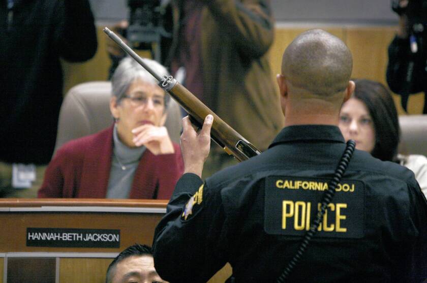 State Sen. Hannah-Beth Jackson (D-Santa Barbara) looks at a semi-automatic rifle during a joint legislative hearing on gun control. Testimony showed some of California’s strict gun laws have been undermined by budget problems.