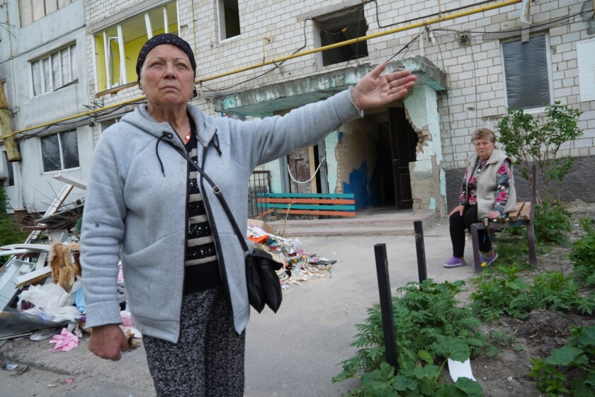 Kadın, ailesinin hasarlı evini işaret ediyor.