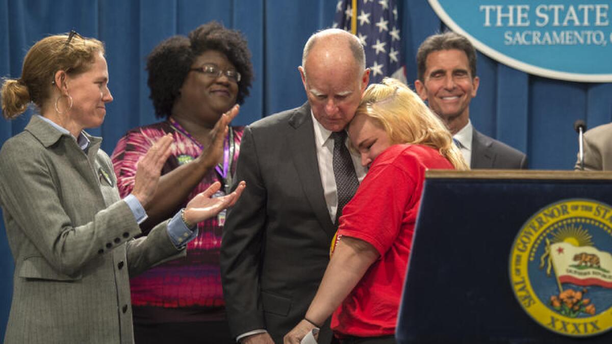 At a Monday press conference, Gov. Jerry Brown hugs Burger King worker Holly Diaz, 38, of Sacramento, who has worked for the minimum wage for nine years.