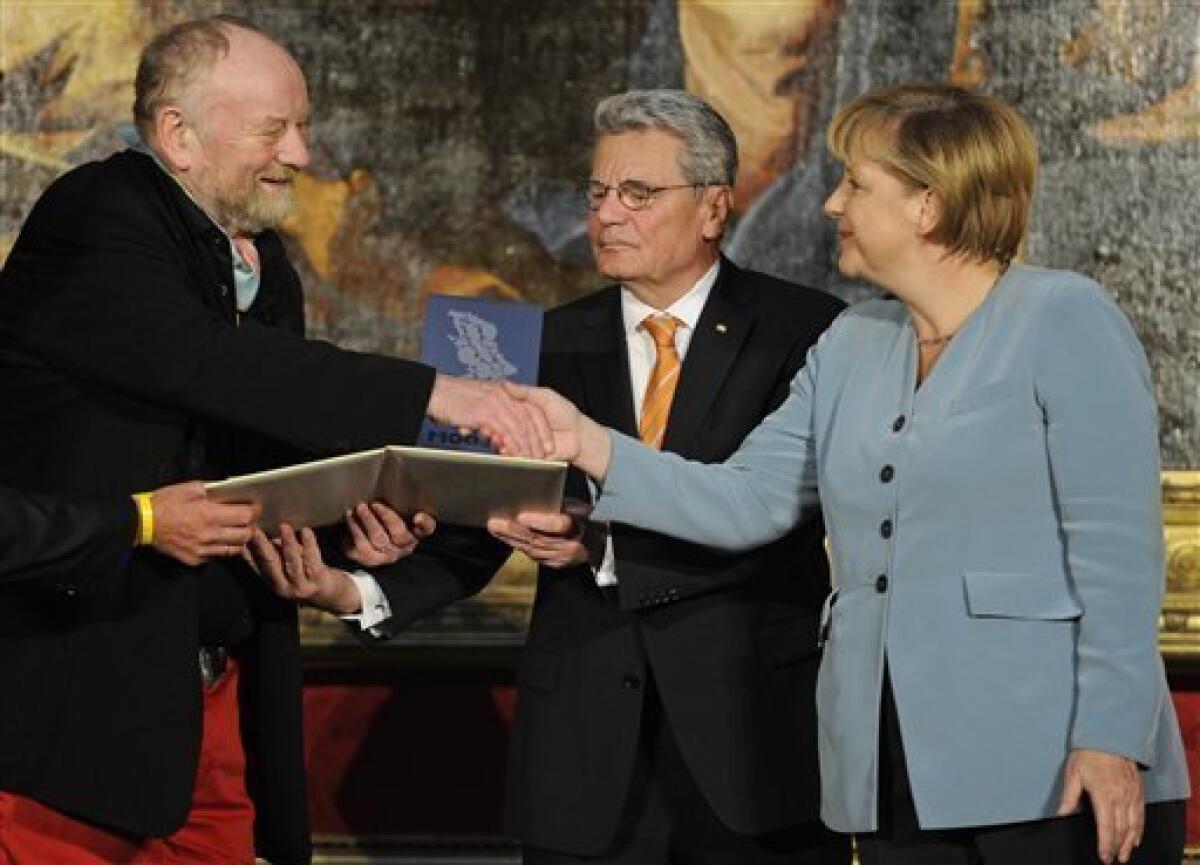 Danish cartoonist Kurt Westergaard, left, is congratulated on his prize by German Chancellor Angela Merkel, right, and the former head of the state-funded body which manages the archives of the former East German secret police Stasi Joachim Gauck, center, after receiving the M100 Media Prize 2010 in Potsdam near Berlin, eastern Germany, Wednesday, Sept. 8, 2010. Westergaard drew the most controversial of 12 caricatures of the Prophet Mohammed, first published in a Danish newspaper in 2005, which many Muslims considered offensive. (AP Photo/Odd Andersen, pool)