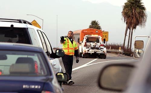 Tow truck driver Tim Hernandez stops traffic on the transition from the northbound 605 Freeway to the 10 Freeway as a stranded bus is moved out of the way. Each year, dozens of pedestrians are killed on Southern California freeways.