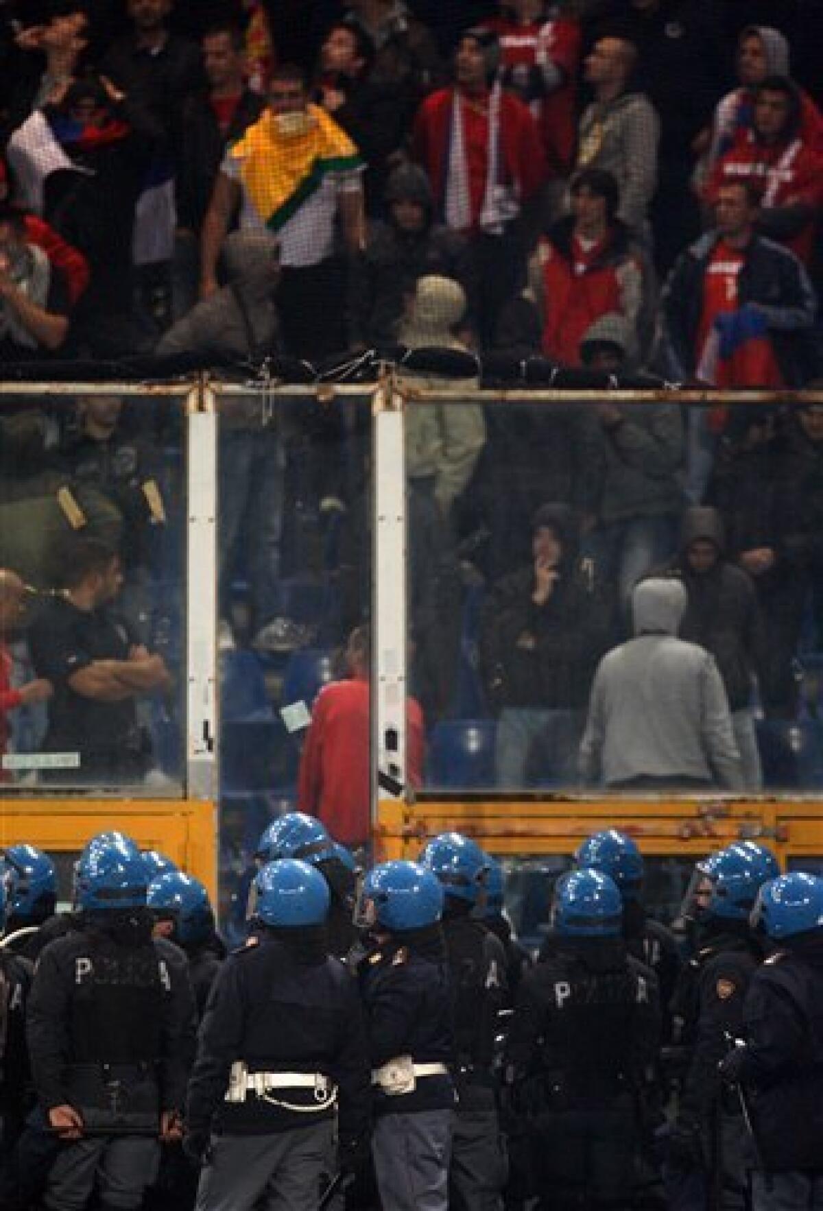 Italian police confront Serbia fans behind a partition prior to the start of a Group C, Euro 2012 qualifying soccer match between Italy and Serbia, at the Luigi Ferraris stadium in Genoa, Italy, Tuesday, Oct. 12, 2010. The Italy-Serbia European Championship qualifier was stopped after seven minutes of play on Tuesday after Serbia fans threw flares onto the pitch. (AP Photo/Antonio Calanni)