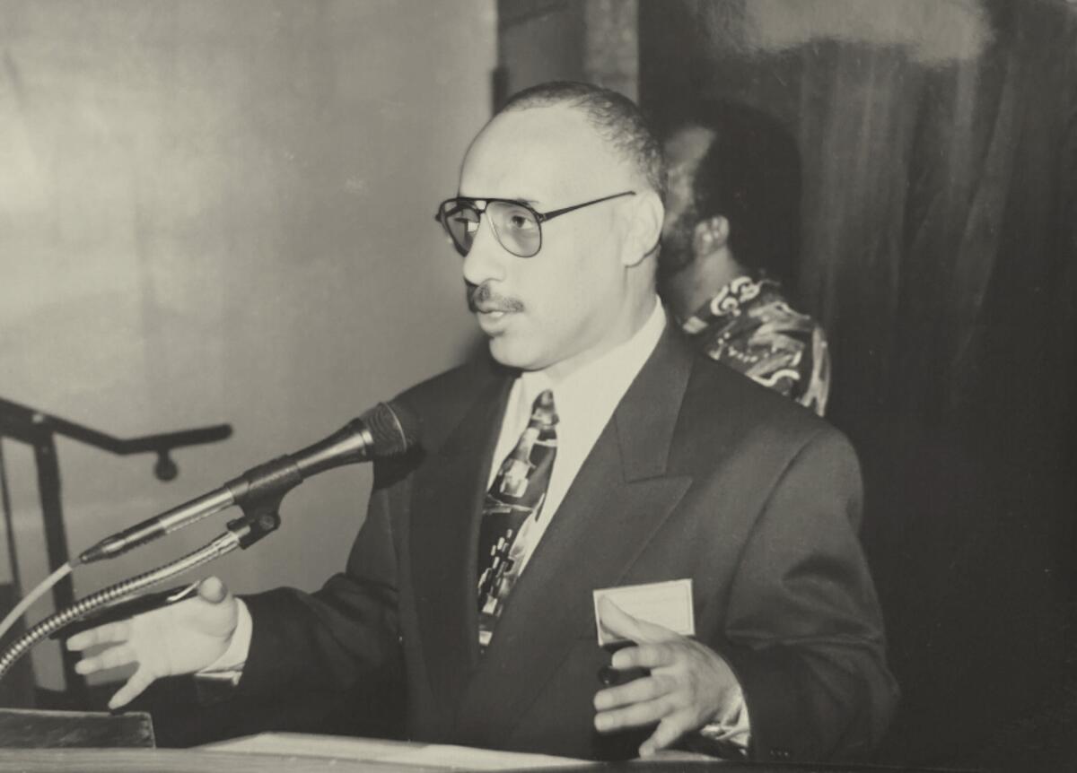 A black-and-white photo of Michael E. Neely speaking into a microphone