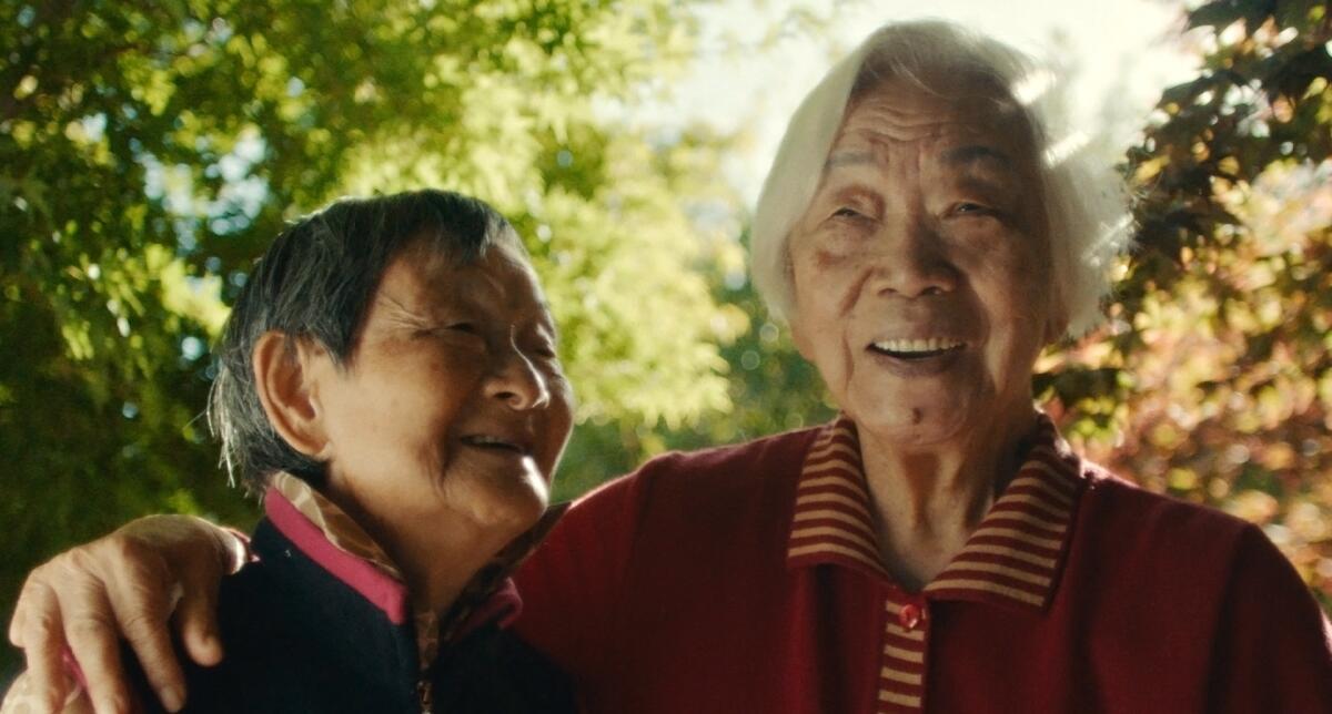 Two old women hug each other and laugh.