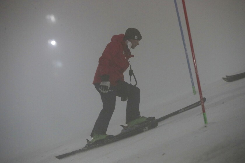 An Austrian team coach checks the foggy course prior to the cancellation of an alpine ski, men's World Cup slalom in Zagreb, Croatia, Wednesday, Jan. 5, 2022. The slalom was cancelled due to the adverse weather conditions. (AP Photo/Gabriele Facciotti)