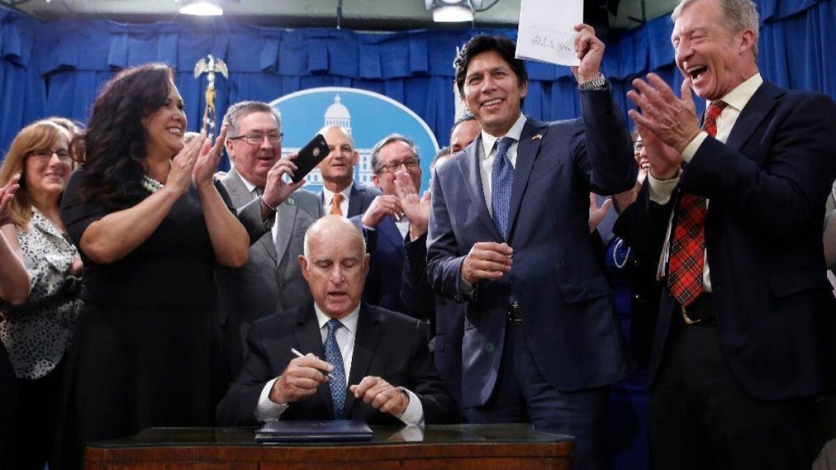 California lawmakers and others celebrate after Gov. Jerry Brown signed SB 100 in Sacramento on Monday, committing the state to 100% clean energy by 2045.