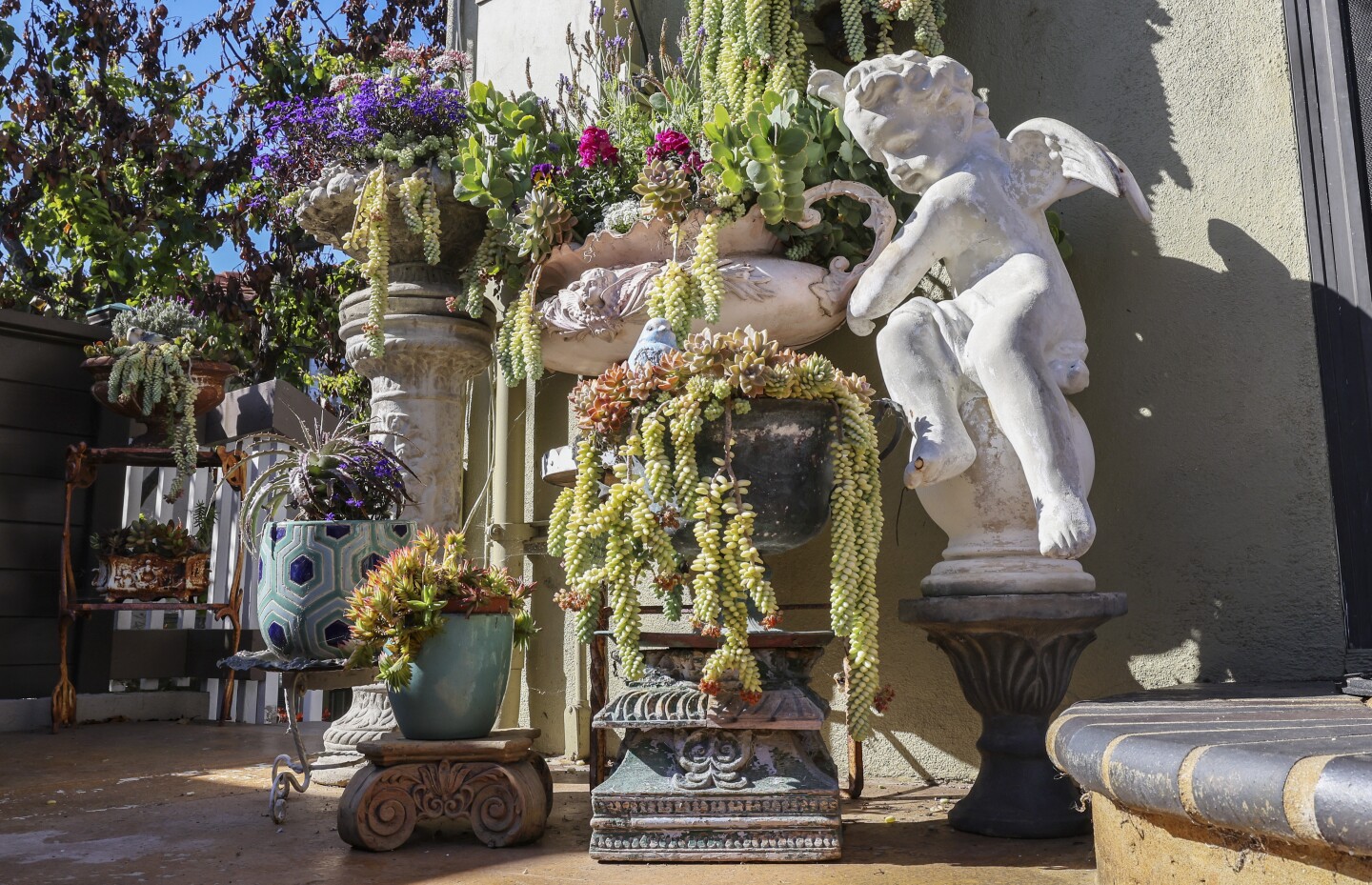 The garden brims with antique religious art and colorful potted plants 