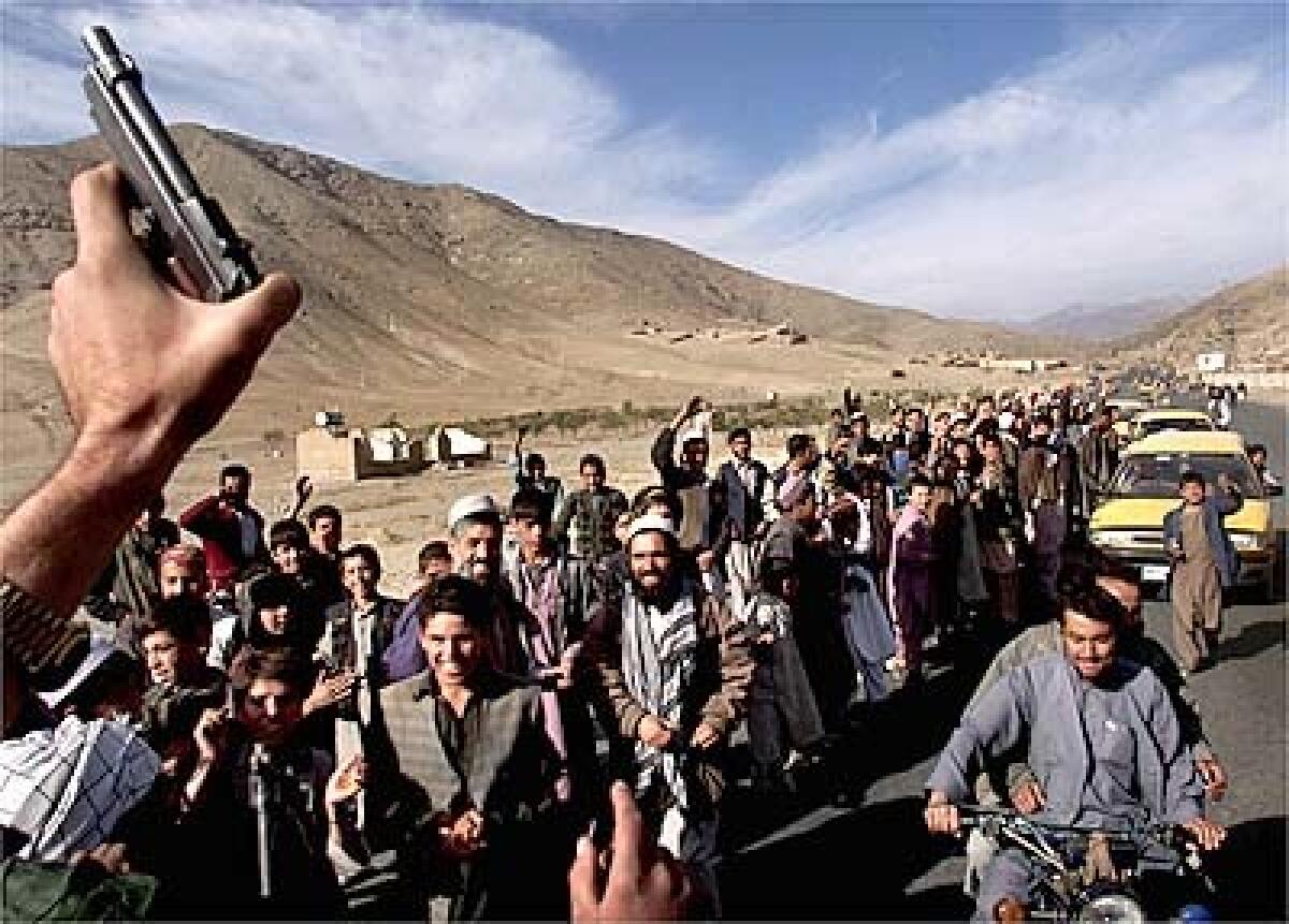 A Northern Alliance soldier waves a pistol in triumph as residents of Kabul line up to greet soldiers Tuesday. From freed prisoners to shopkeepers, many residents of the Afghan capital were celebrating the departure of Taliban forces from the city