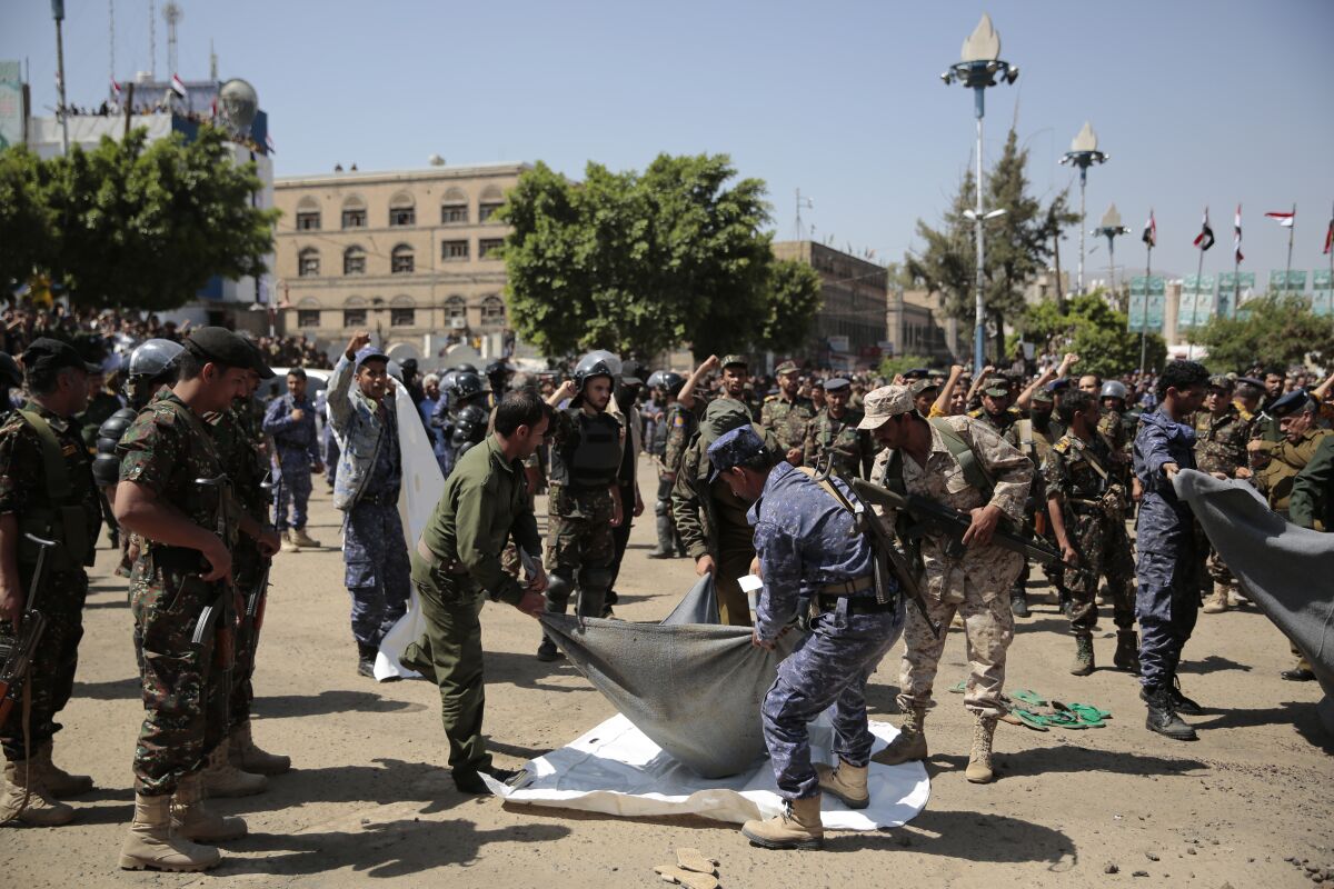 Police carry the body of a man executed in Tahrir Square in Sana, Yemen
