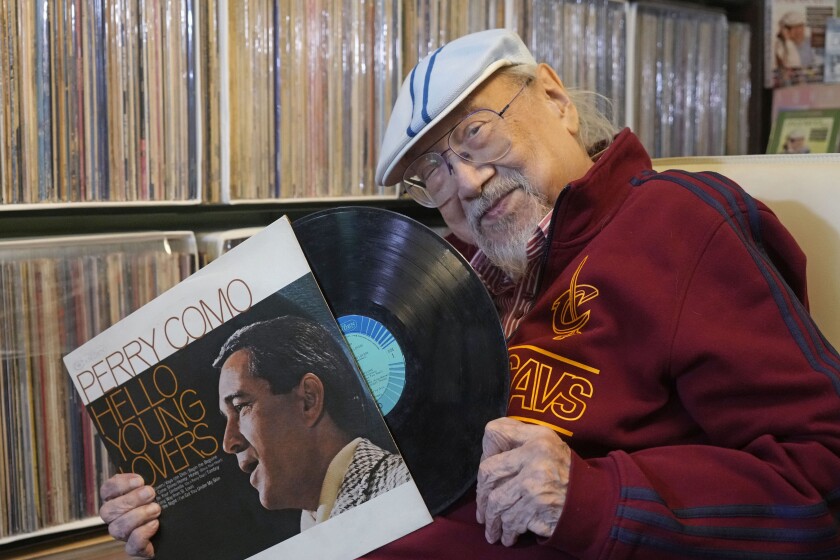 Ray Cordeiro, Hong Kong's oldest DJ shows a vinyl record at his home in Hong Kong, Thursday, May 27, 2021. Cordeiro has been named the world's "most durable DJ" by the Guinness Book of World Records, Hong Kong veteran Disc Jockey 96-yer-old Ray Cordeiro, hanged up his headphones for good after seven decades of entertaining listeners by a mix of pop oldies mainly from 60s and 70s, from the Beatles to the Rolling Stones to classics like Sinatra and Tony Bennett. (AP Photo/Kin Cheung)