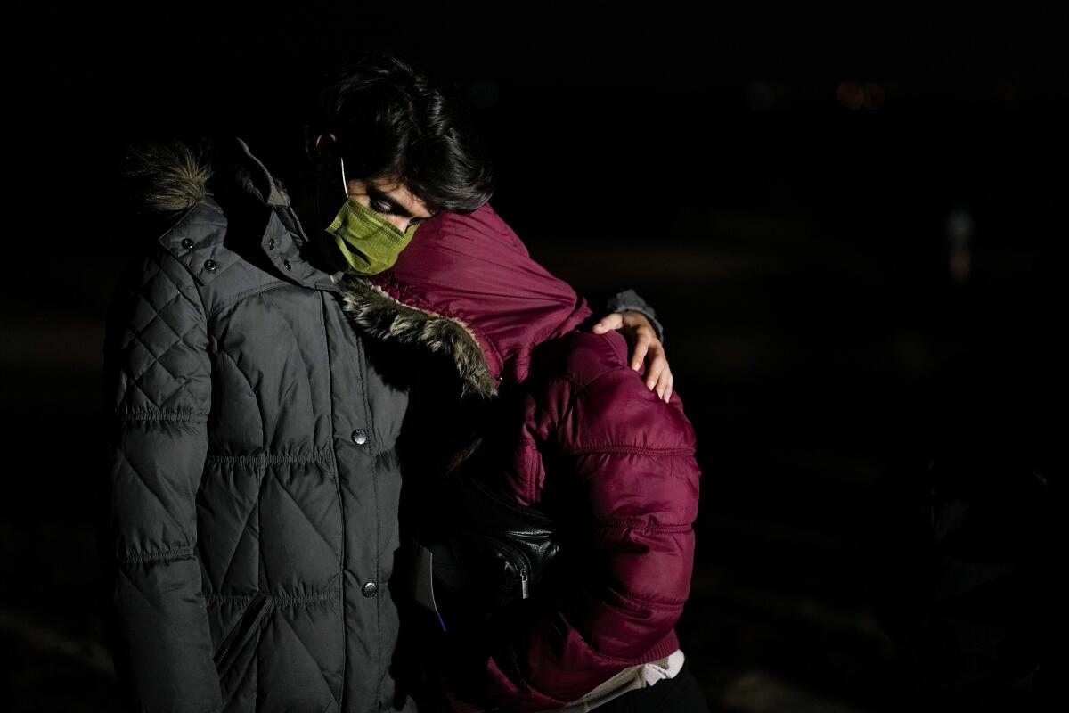 El migrante cubano Mario Pérez abraza a su esposa mientras esperan solicitar asilo luego de cruzar la frontera a Estados