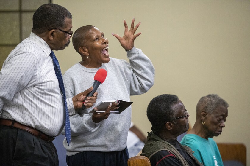 Jonathan Taylor, left, an official with the National Assn. for Equal Justice in America, holds the microphone for Gilda Blueford, a Compton resident, as she questions actions by the L.A. County Sheriff's Department during a town hall meeting Thursday night.