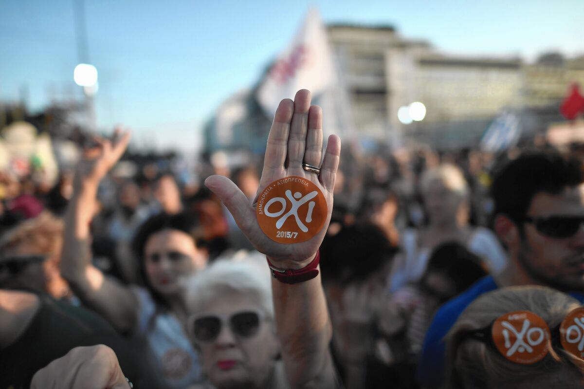 A demonstrator flashes a “no” sticker at an Athens rally for the referendum Sunday on a financial bailout package for Greece.