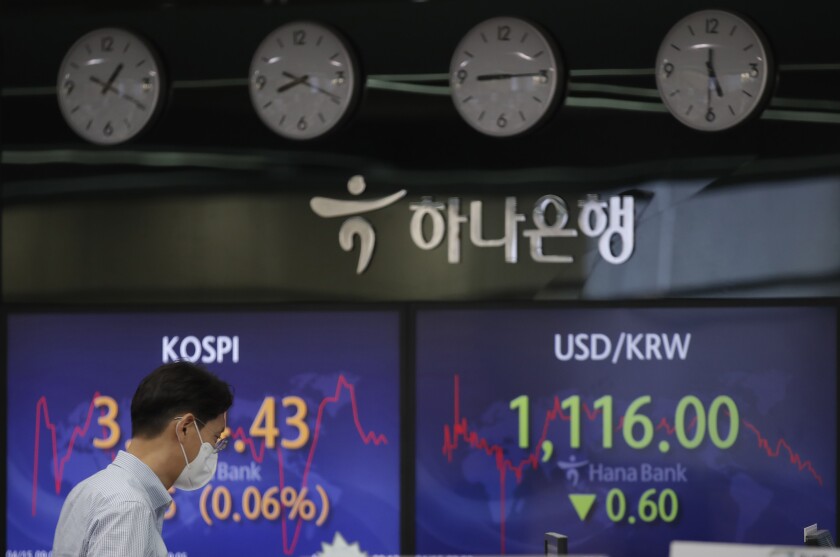 A currency trader walks by the screens showing the Korea Composite Stock Price Index (KOSPI), left, and the foreign exchange rate between U.S. dollar and South Korean won at the foreign exchange dealing room in Seoul, South Korea, Thursday, April 15, 2021. Asian stock markets were mixed Thursday after Wall Street retreated from a record high as major banks reported strong profits at the start of U.S. earnings season. (AP Photo/Lee Jin-man)