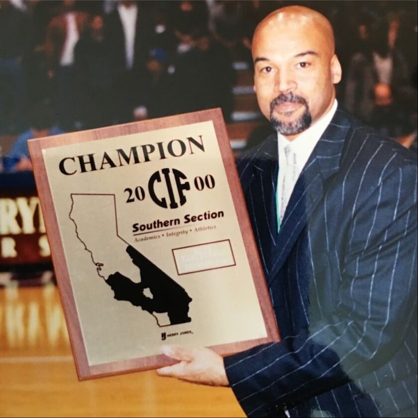 Coach Michael Lynch holds up a CIF Southern Section championship plaque.