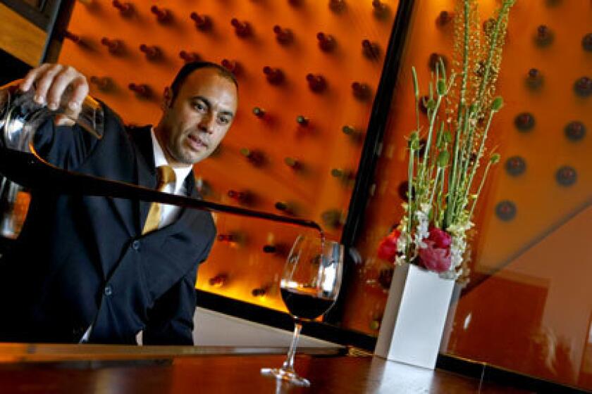 Wine sommelier Sylvester Fernandes pours wine at Patina, an elegant restaurant at the Walt Disney Concert Hall in Los Angeles. The Times review of Patina