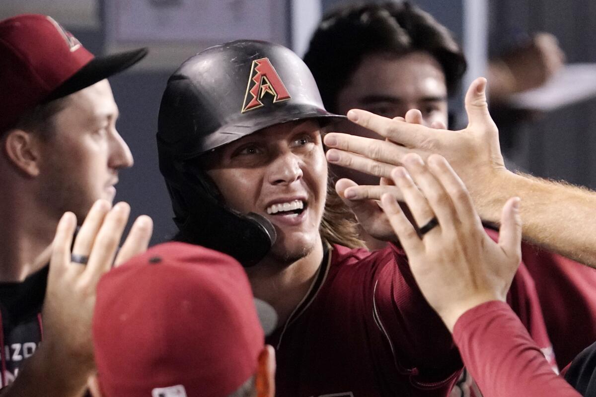 Arizona Diamondbacks' Jake McCarthy is congratulated by teammates in the dugout after scoring on a single by Christian Walker during the third inning of a baseball game against the Los Angeles Dodgers Wednesday, Sept. 21, 2022, in Los Angeles. (AP Photo/Mark J. Terrill)