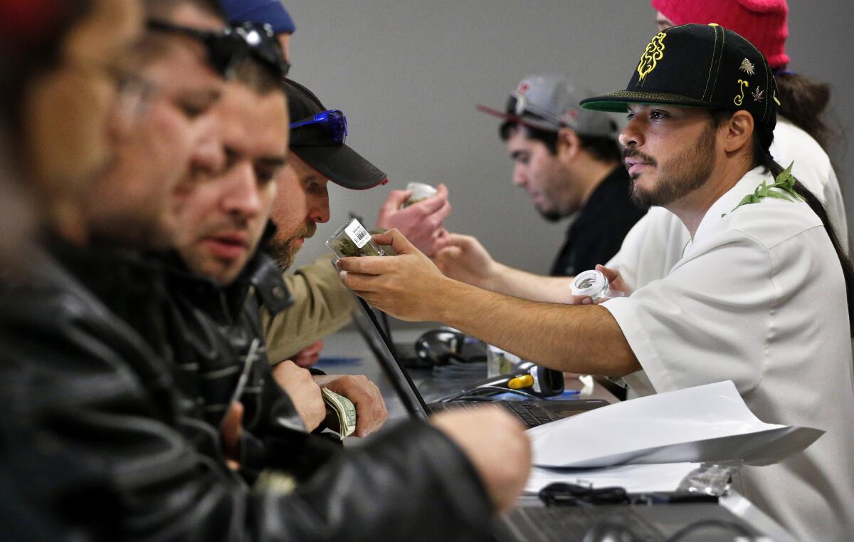 David Marlow, right, helps a customer, who smells a strain of marijuana before buying it, at the crowded sales counter inside a marijuana retail store in Denver on Jan. 1.